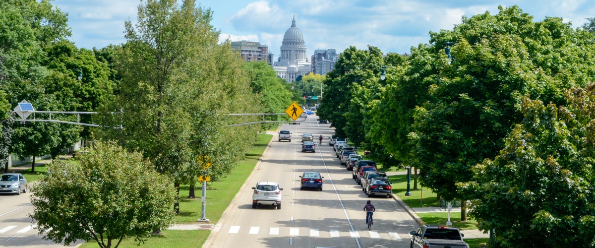 Cars driving on a road next to a bike path with cyclists riding along it